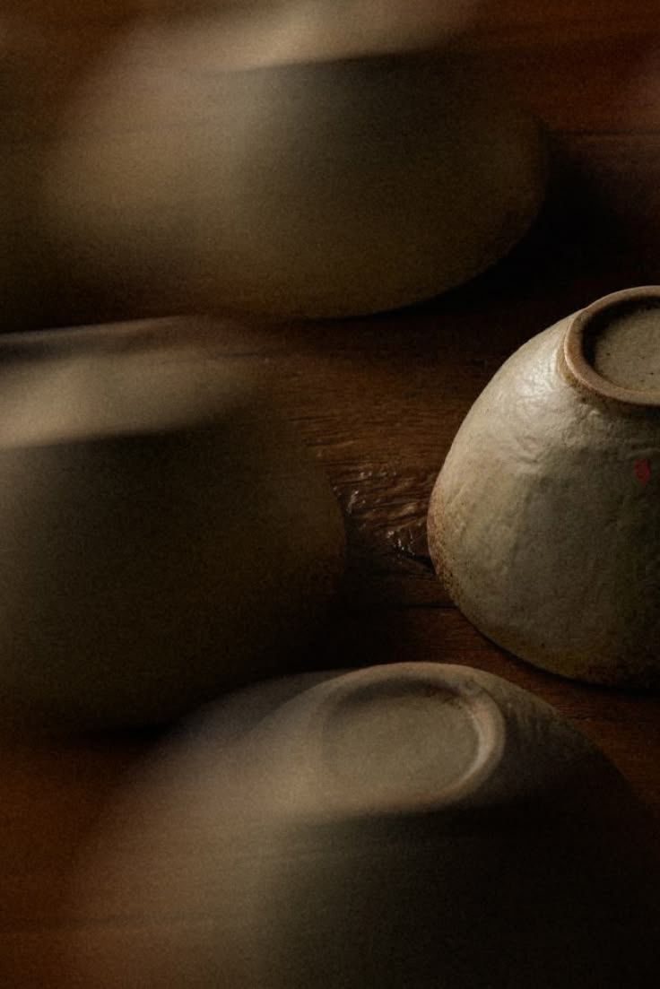 Dark wabi-sabi ceramic bowls resting in low light — a study in quiet material.